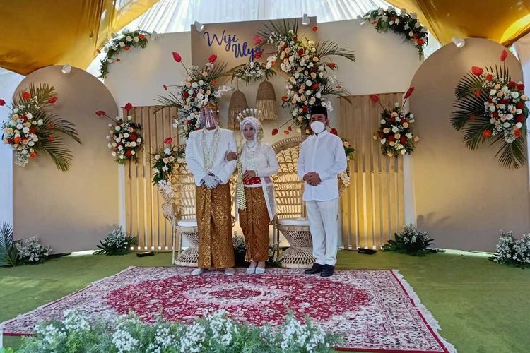 Foto sesi pertama saat Haryanto mengenakan masker berdiri berdampingan dengan sepasang pengantin di Kecamatan Batangan, Kabupaten Pati, Jawa Tengah, Minggu (17/1/2021).