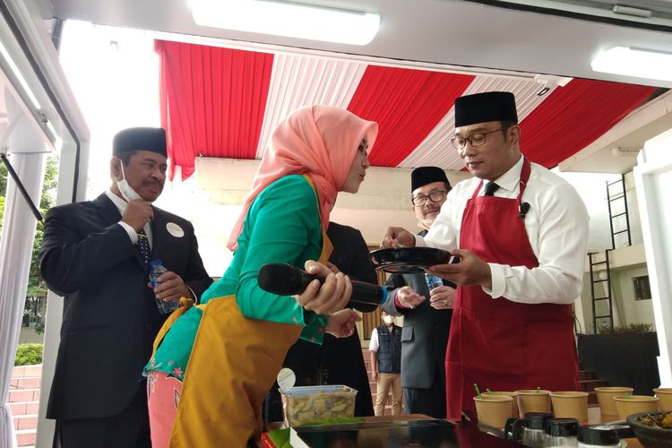 Gubernur Jawa Barat Ridwan didampingi istrinya, Atalia Praratya, memasak jengkol sambal lado hijau yang mengambil resep dari buku kuliner nusantara bernama Mustikarasa dalam merayakan puncak Hari Ibu ke-93 di Jalan Soekarno, Kota Bandung, Rabu (22/12/2021). 