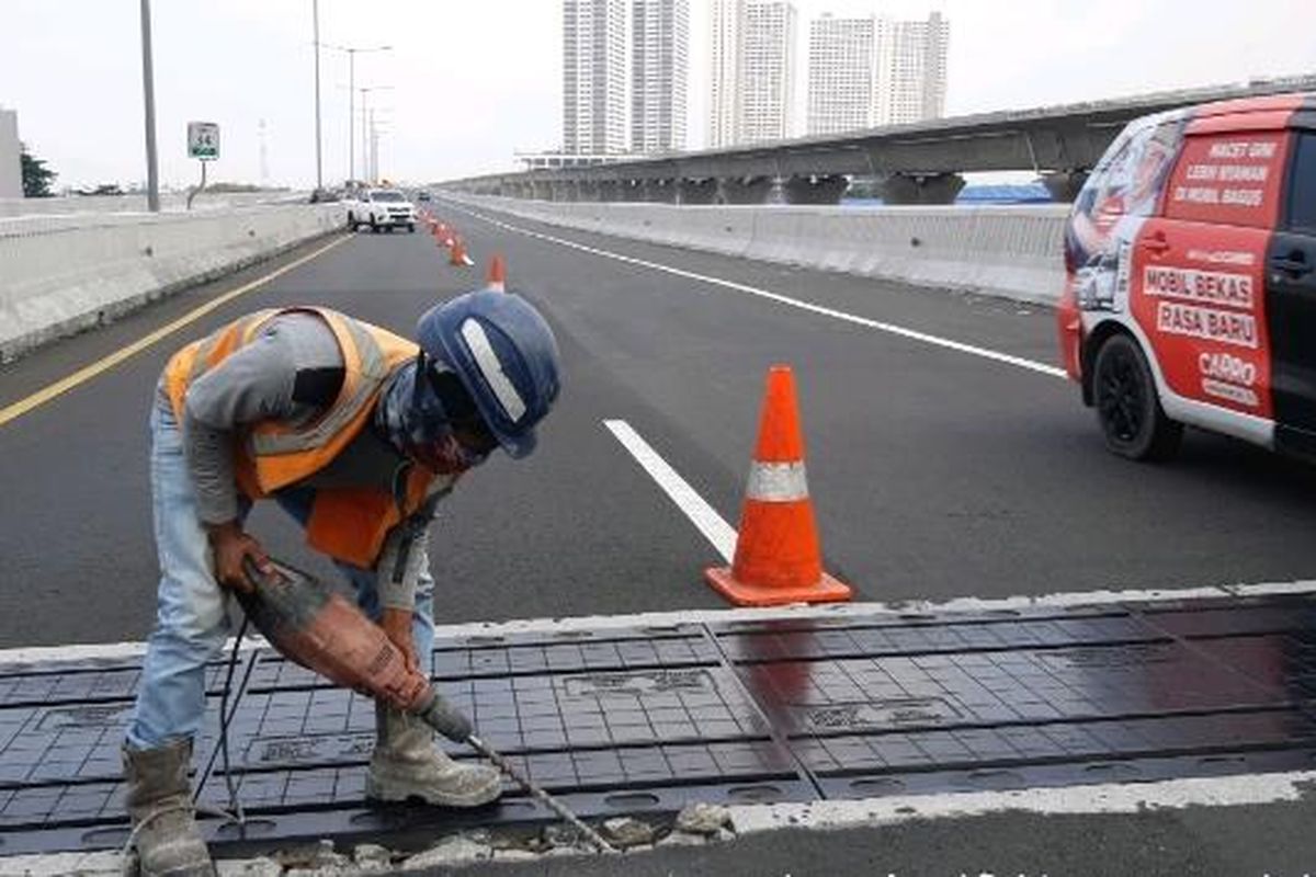 Salah satu tenaga kerja sedang memasang siar muai atau expansion joint di Jalan Tol Layang Mohammed Bin Zayed, Jakarta, Minggu (22/8/2021).