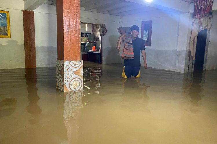 Seorang warga korban banjir di Desa Talikumain, Kecamatan Tambusai, Kabupaten Rokan Hulu, Riau, Dermawansyah (29) menaikkan beberapa peralatan rumah tangga ke lantai dua rumahnya, Kamis (28/12/2023).