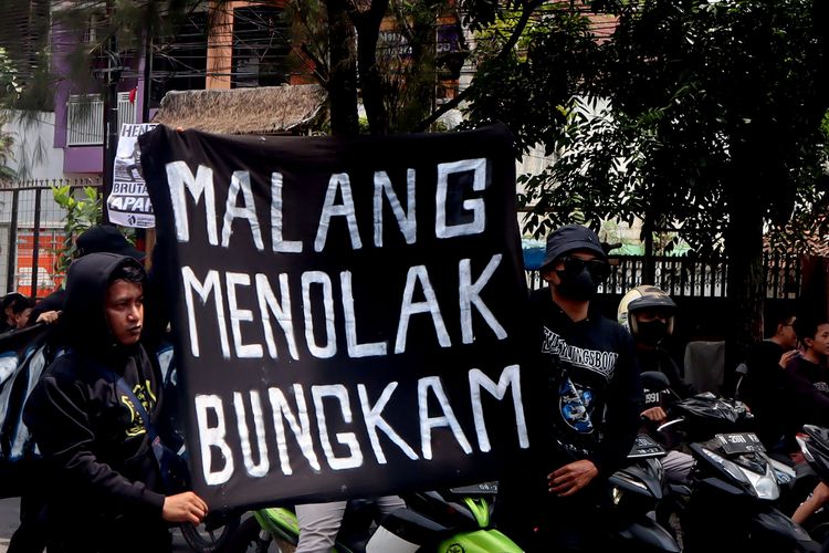 Suporter Arema, Aremania membentangkan spanduk saat melakukan aksi damai Tragedi Kanjuruhan menuntut keadilan yang dilaksanakan di 18 titik Kota Malang, Minggu (20/11/2022) siang.