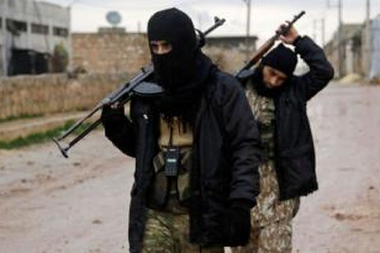 Dua orang pemberontak Suriah sedang berjalan sambil menenteng senjata di sebuah desa di kota Aleppo. AS berencana akan melatih ribuan anggota pemberontak berhaluan moderat untuk memerangi ISIS.