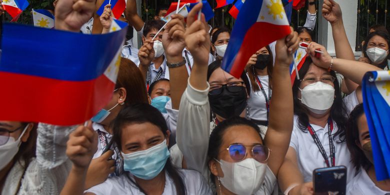 Government employees wave their national flags as they await the arrival of their new Philippine President Ferdinand Marcos Jr. at the Malacanang presidential palace, following his inauguration ceremony in Manila on June 30, 2022. (Photo by Maria Tan / AFP)