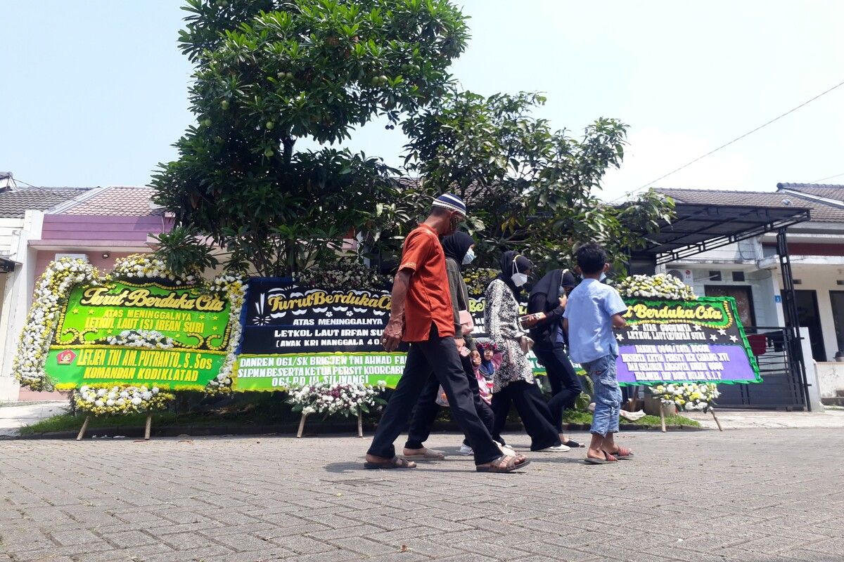 Sejumlah pelayat melintasi karangan bunga belasungkawa di kediaman rumah duka salah satu awak kapal selam KRI Nanggala-402 Letkol Irfan Suri, di Perumahan Bogor Nirwana Residence, Cluster Harmoni 2, Bogor, Jawa Barat, Senin (26/4/2021).