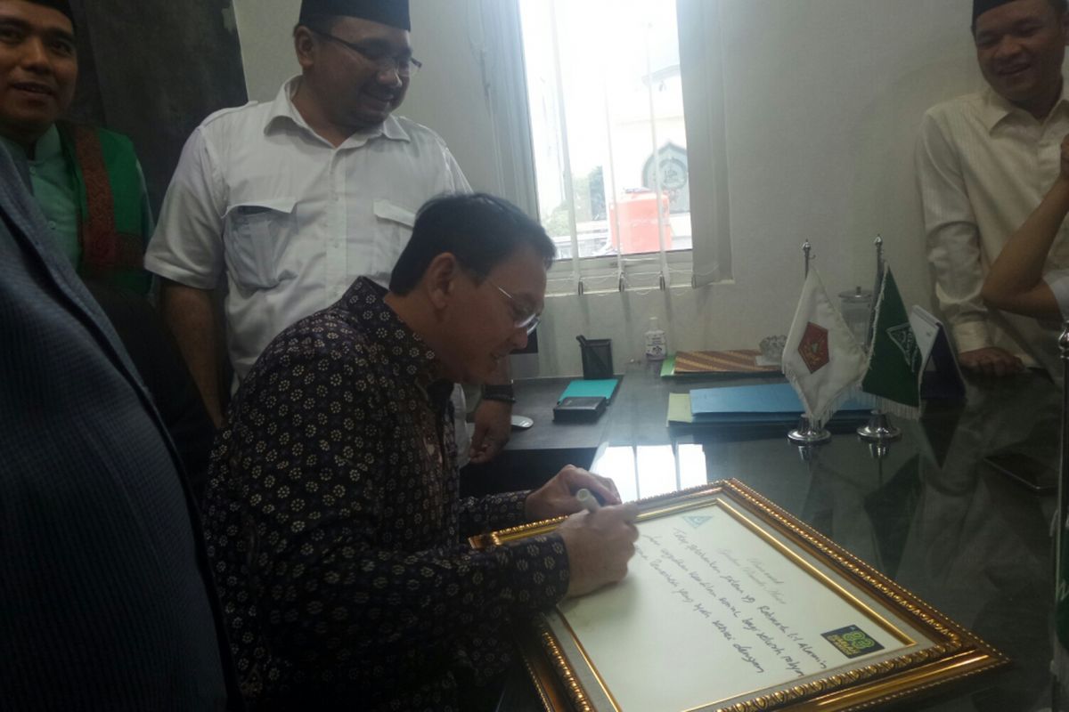 Calon gubernur DKI Jakarta Basuki Tjahaja Purnama menulis pesan untuk GP Ansor, di Jalan Kramat Raya, Jumat (7/4/2017). 