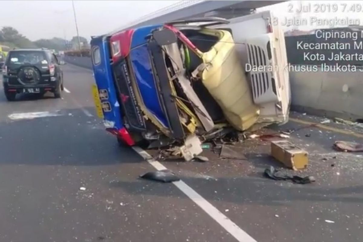 Truk terbalik setelah tabrak pembatas jalan di Tol Jakarta-Cikampek KM 03, Makasar, Jakarta Timur, Selasa (2/7/2019).