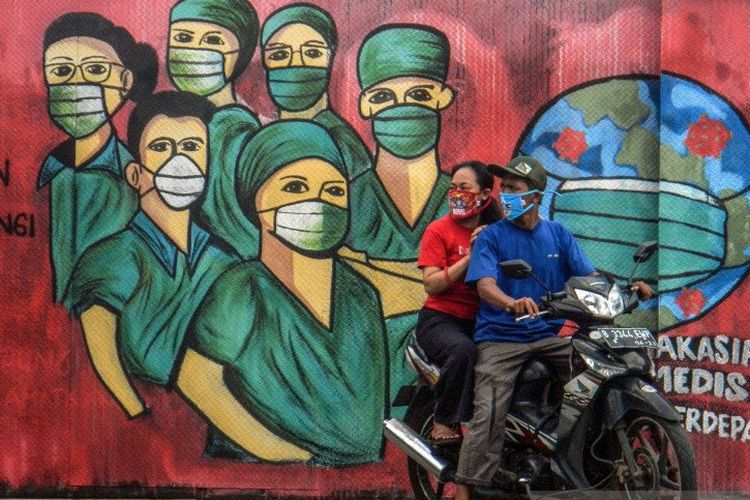 Pengendara motor melintas di depan mural tentang pandemi virus corona atau COVID-19 di Jalan Raya Jakarta-Bogor, Depok, Jawa Barat, Jumat (3/4/2020). Mural tersebut ditujukan sebagai bentuk dukungan kepada tenaga medis yang menjadi garda terdepan dalam menghadapi COVID-19 di Indonesia. 