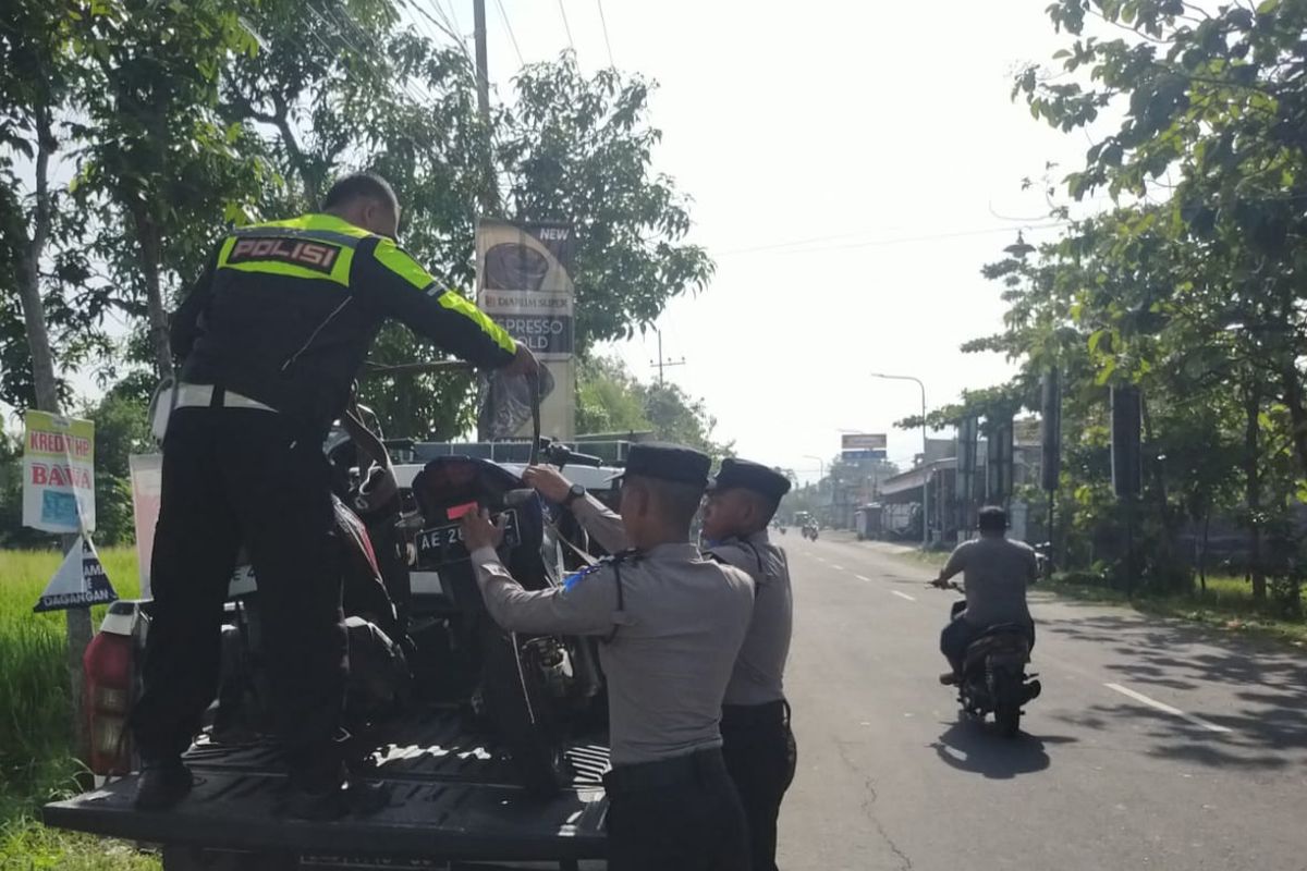 Polisi menaikkan dua sepeda motor yang terlibat kecelakaan di ruas jalan jurusan Geger ? Dagangan, Desa Dagangan, Kecamatan Dagangan, Kabupaten Madiun, Jawa Timur untuk diangkut ke atas mobil, Rabu (20/11/2024).