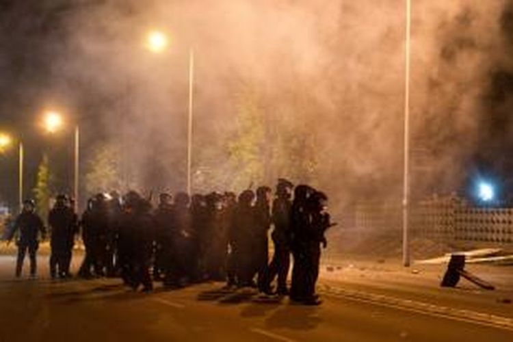 Polisi Jerman bersiaga di depan bangunan yang dijadikan penampungan pengungsi di kota Heidenau dekat Dresden, Sabtu (22/8/2015), setelah ratusan orang aktivis sayap kanan menentang pembangunan pusat-pusat penampungan pengungsi itu.