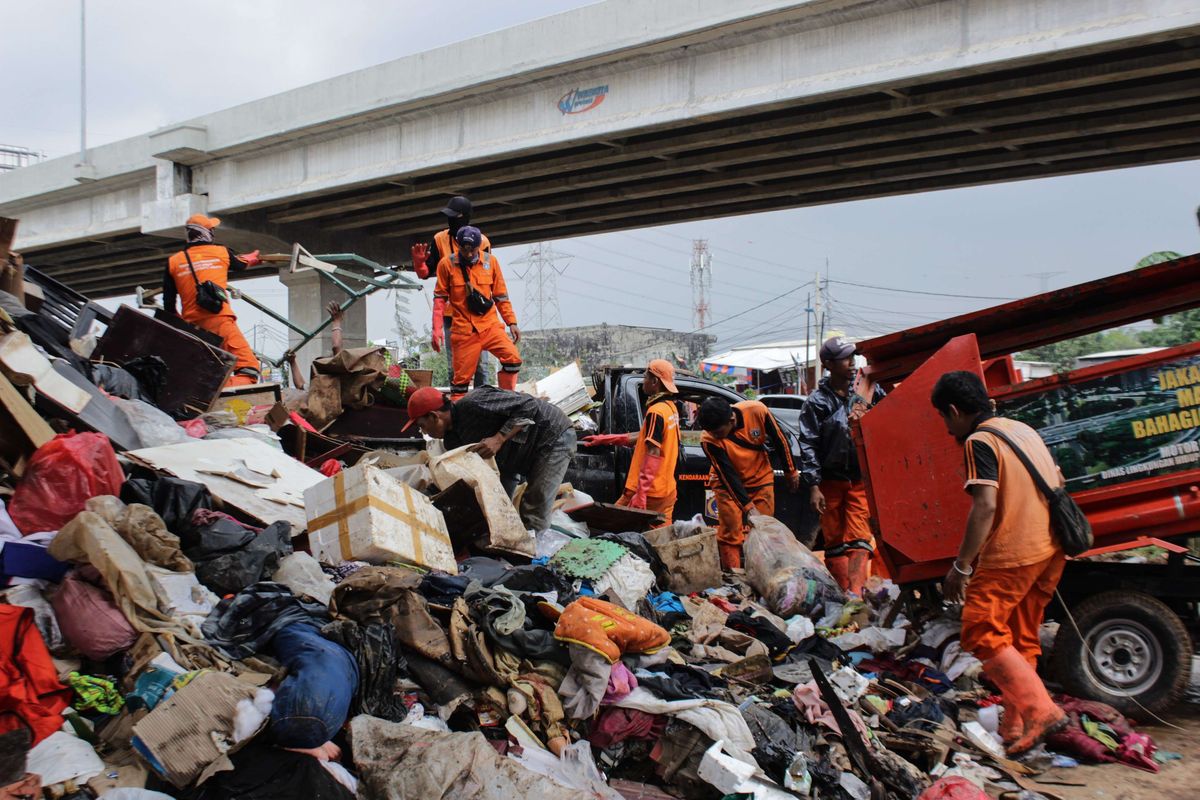 Para petugas Penanganan Prasarana dan Sarana Umum (PPSU) DKI Jakarta mengangkut sampah yang menggunung di bawah Tol Becakayu, Cipinang Melayu, Jakarta Timur, Rabu (8/1/2020). Tumpukan sampah ini berasal dari perumahan warga RW 03, 04, 10, 11, dan 12 Cipinang Melayu, Jakarta Timur.