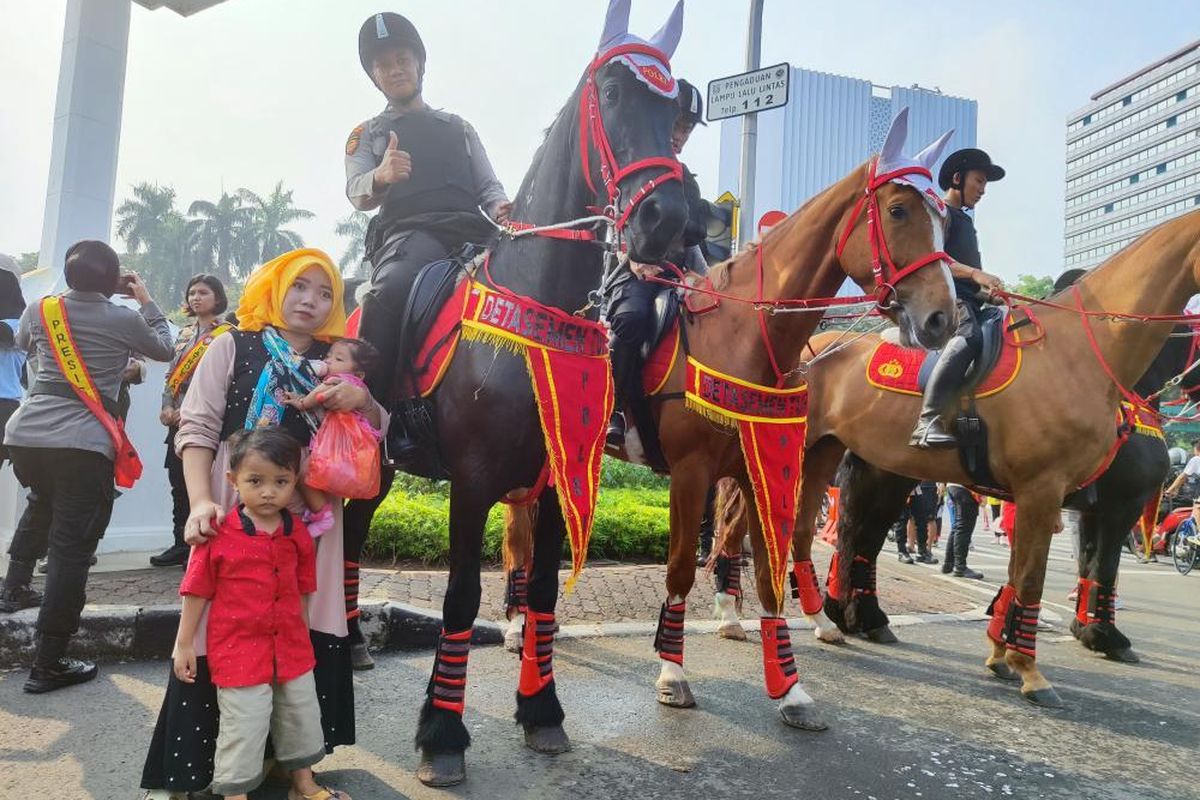 Warga antusias berfoto dengan kuda kepolisian di depan Monas saat CFD, Minggu (25/6/2023) 