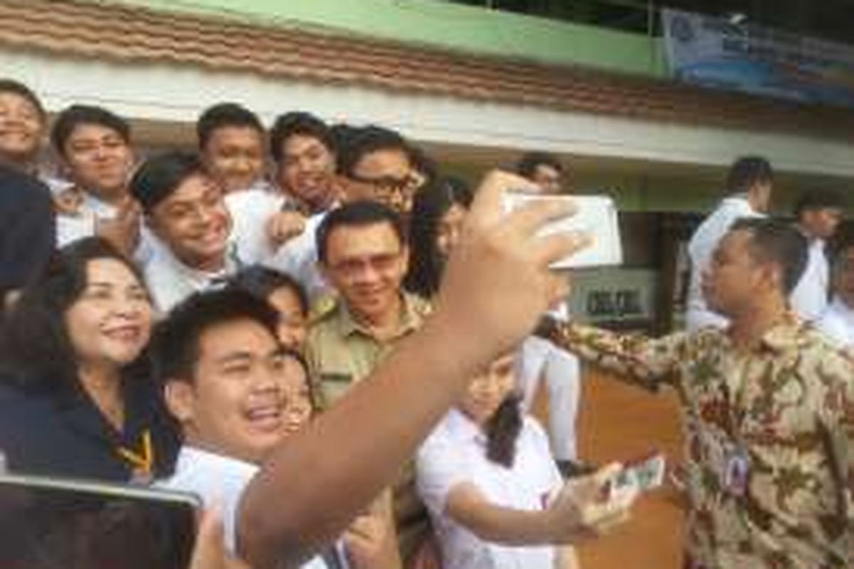 Gubernur DKI Jakarta Basuki Tjahaja Purnama berselfie bersama para siswa SMA 30 Jakarta jelang pelaksanaan hari pertama Ujian Nasional 2016 di SMA 30 Jakarta di Cempaka Putih, Jakarta Pusat, Senin (4/4/2016).