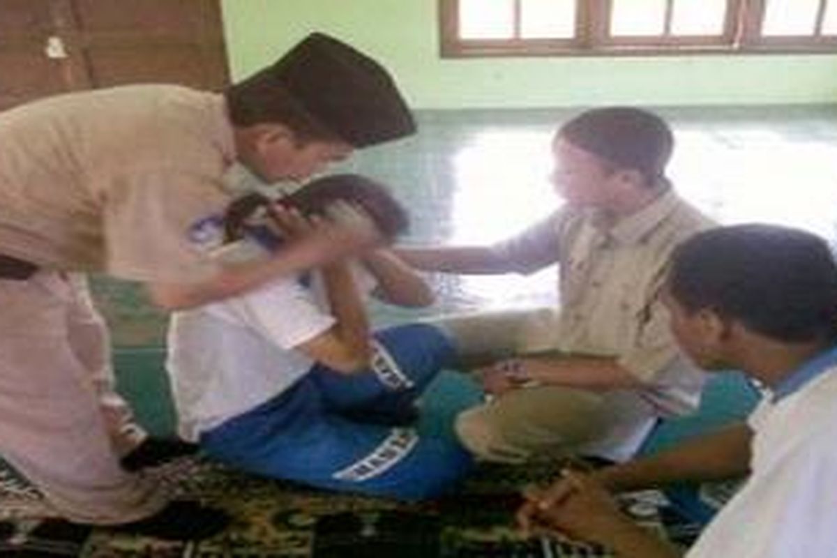 Seorang guru membantu menenangkan siswi yang sedang kesurupan