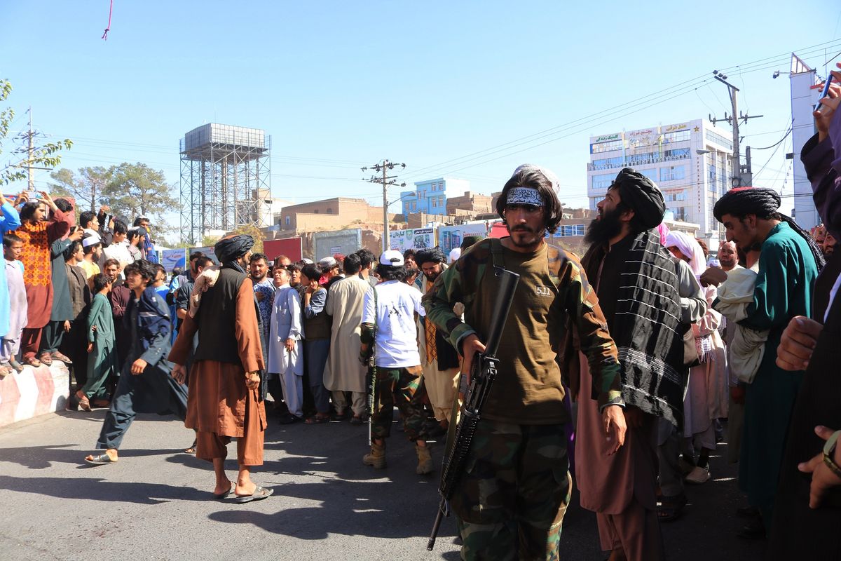 Orang-orang berkumpul di alun-alun kota Herat di barat Afghansitan, di mana Taliban menggantung mayat terduga penculik menggunakan crane pada Sabtu, 25 September 2021. Taliban mengumumkan jasad itu digantung sebagai peringatan jika ada yang hendak berbuat jahat.