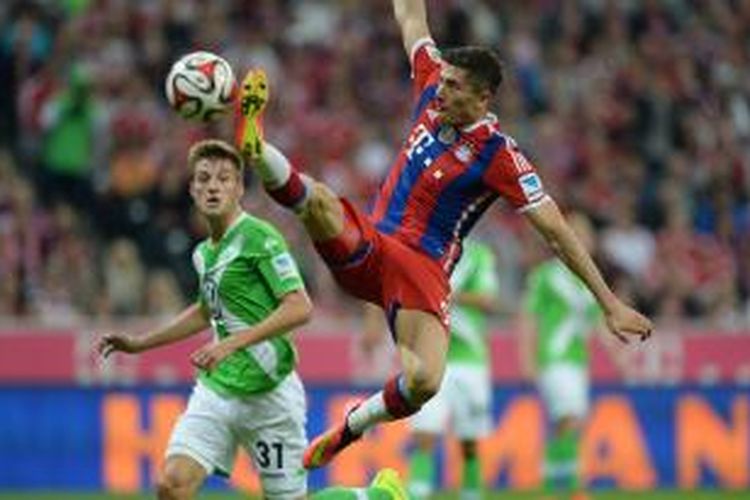 Penyerang Bayern Muenchen, Robert Lewandowski (kanan) berebut bola dengan bek Wolfsburg Robin Knoche pada laga perdana Bundesliga 2014/15 di Allianz Arena, Jumat (22/8/2014).