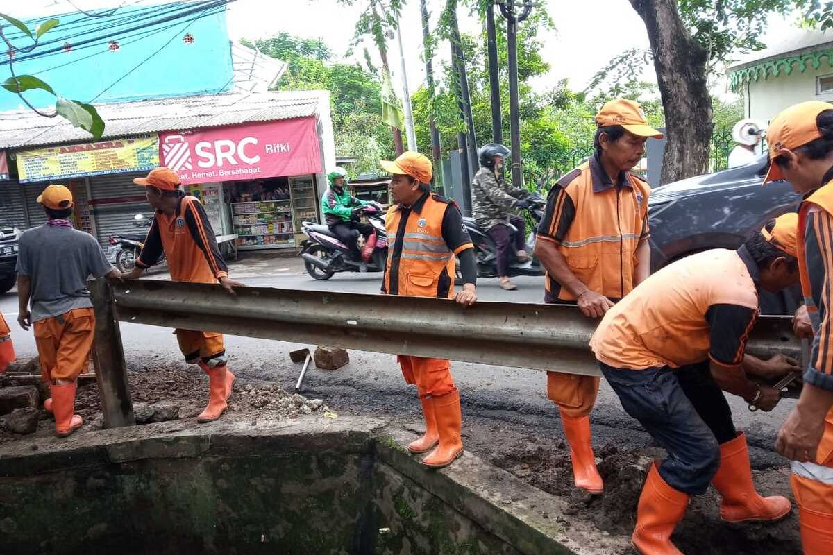 Petugas PPSU Kelurahan Setu saat memasang guard rail atau pembatas jalan di Jalan Raya Pagelarang, Setu, Jakarta Timur, Jumat (31/1/2020).
