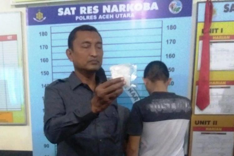 Kasat Narkoba Polres Aceh Utara, AKP Ildani Ilyas memperlihatkan sabu-sabu dan tersangka yang ditembak pada bagian kaki di Mapolres Aceh Utara, Sabtu (6/10/2018)