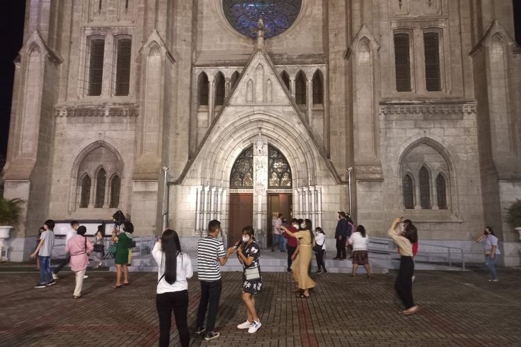 Sejumlah jamaah menyempatkan diri untuk berswafoto di depan Gereja Katedral, Jakarta Pusat usai misa tatap muka terbatas, Jumat (24/12/2021).