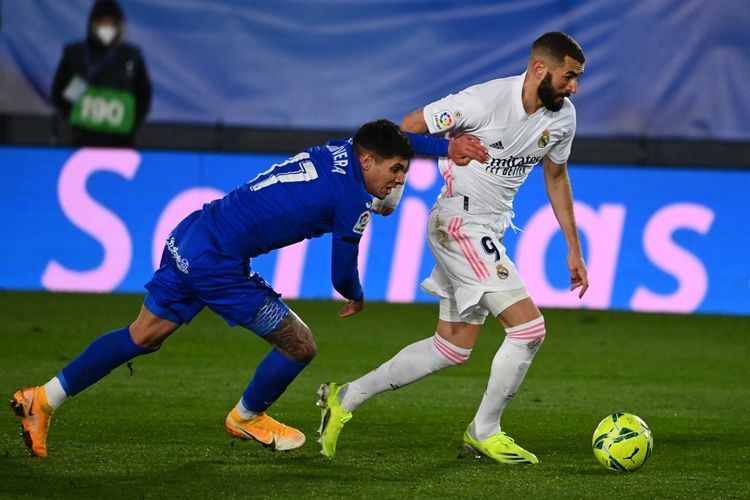 Karim Benzema dibayangi oleh Mathias Olivera dalam laga Real Madrid vs Getafe pada partai tunda pekan pertama Liga Spanyol 2020-2021 yang digelar di Stadion Alfredo di Stefano, Valdebebas, Selasa (9/2/2021) malam waktu setempat. (Photo by GABRIEL BOUYS / AFP)