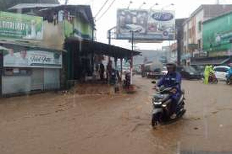 Warga membuka penutup selokan di kawasan Batu Merah untuk menolong seorang kakak yang tersert banjir, Sabtu (16/7/2016)