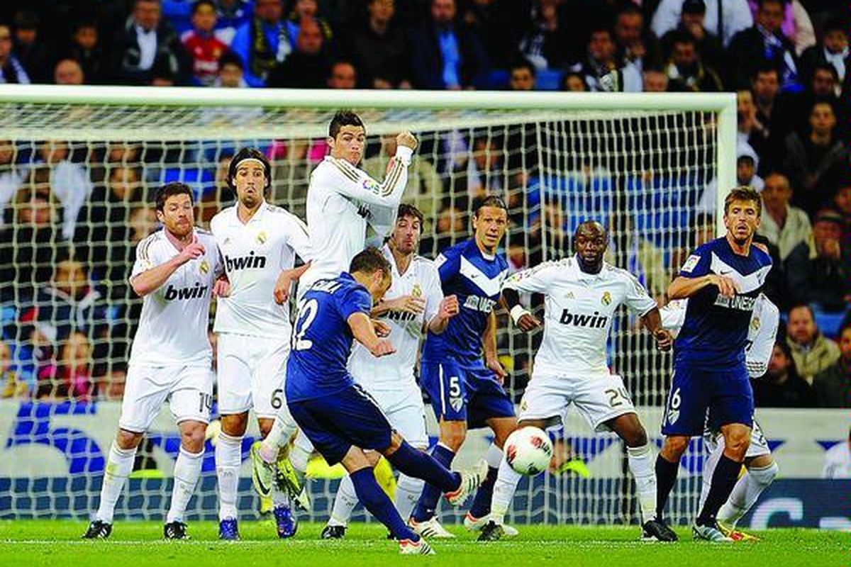 Tendangan bebas gelandang Malaga, Santi Cazorla (tengah), menembus pagar pertahanan Real Madrid dan gol pun tercipta pada laga Liga Spanyol di Stadion Santiago Barnabeu, Madrid, Minggu (18/3). El Real ditahan Malaga 1-1.