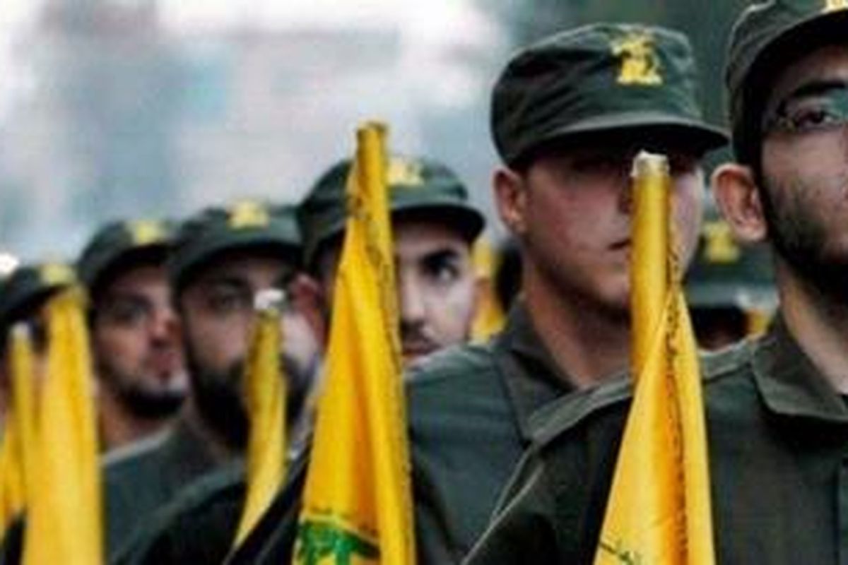 Para pejuang Hezbollah berbaris membawa panji-panji organisasinya.