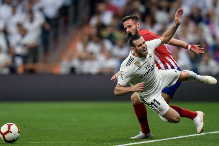 Pemain Real Madrid, Gareth Bale, terjatuh saat berduel dengan pilar Atletico Madrid, Saul Niguez, dalam pertemuan kedua tim pada laga pekan ke-7 Liga Spanyol di Santiago Bernabeu, Sabtu (29/9/2018). 