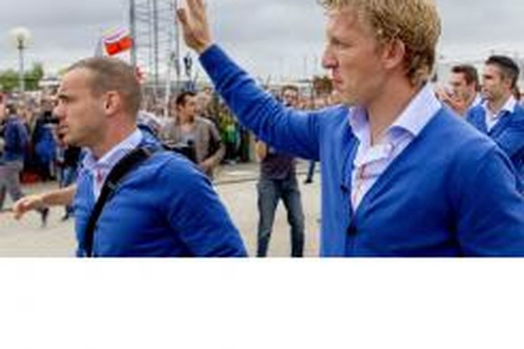 Penyerang Belanda, Dirk Kuyt (kanan), melambaikan tangana kepada pendukung, begitu juga dengan rekan setimnya, Wesley Sneijder, ketika tiba di bandar udara Rotterdam-The Hague, di Rotterdam, 13 Juli 2014. Belanda menempati peringkat ketiga Piala Dunia 2014 setelah menang 3-0 atas tuan rumah, Brasil, pada 12 Juli.