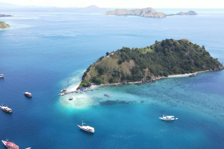 Panorama pantai dan kapal turis di Pulau Kelor, Taman Nasional Komodo, Labuan Bajo.