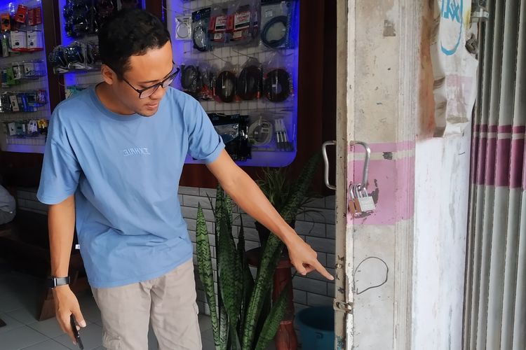 KEMALINGAN: Pemilik toko saat menunjukkan pintu yang rusak karena dicongkel maling.