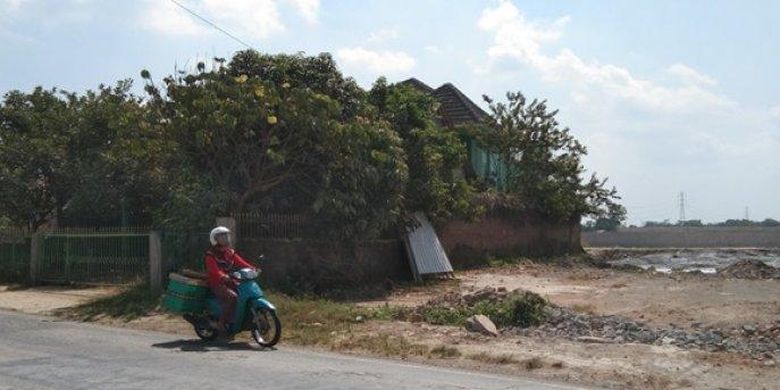 Seorang pengendara sepeda motor melintas di depan rumah yang kokoh berdiri di sekitar proyek Tol Yogyakarta-Solo di Kahuman, Ngawen, Klaten, Kamis (11/8/2022) 
