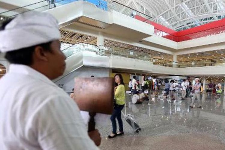 Seorang pemandu wisata menjemput wisatawan di terminal kedatangan internasional Bandara Ngurah Rai, Bali, Rabu (12/3/2014). Kunjungan wisatawan ke Bali masih terpantau ramai menjelang Hari Raya Nyepi.