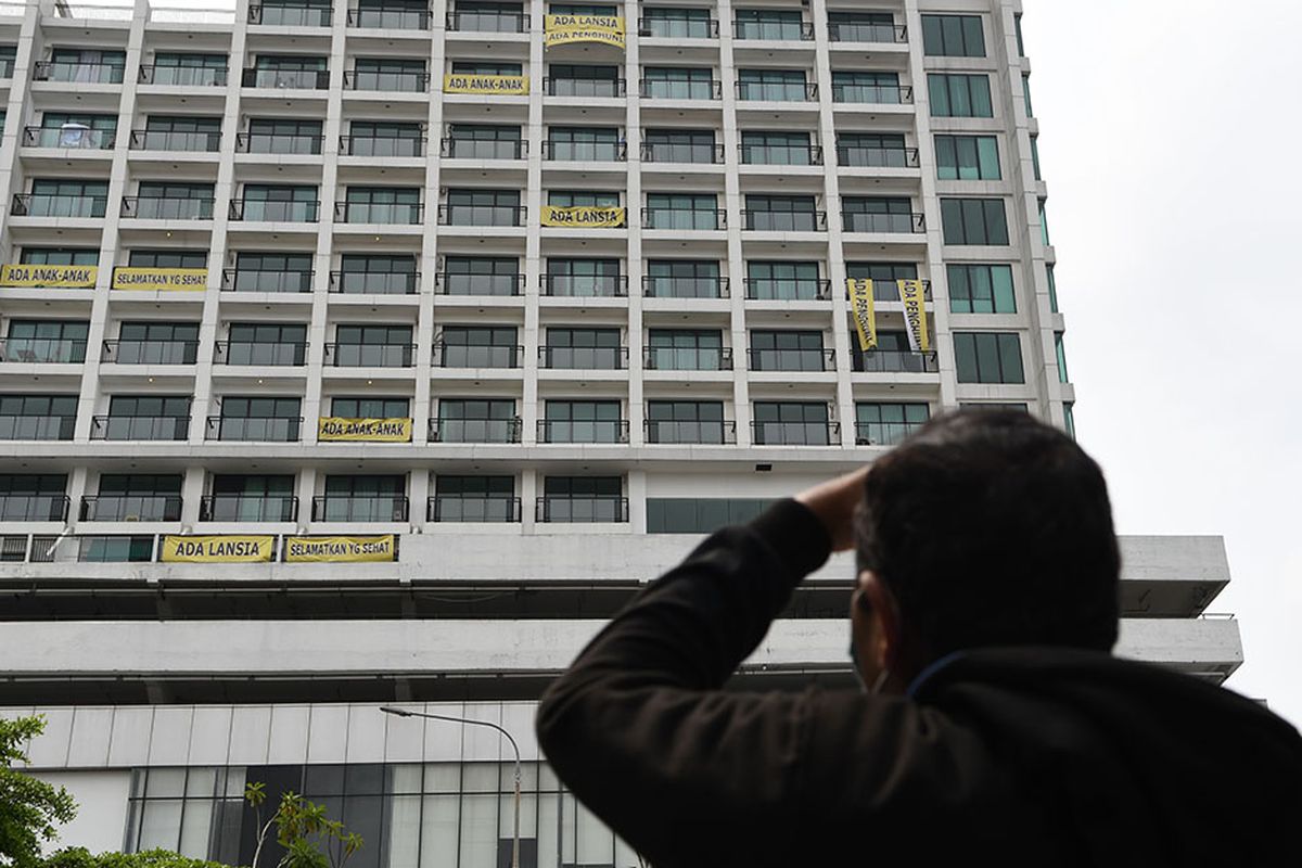 Warga mengamati spanduk bertuliskan penolakan atas penggunaan rumah sakit darurat COVID-19 yang terpasang di Lippo Plasa, Mampang, Jakarta, Minggu (5/4/2020). Aksi tersebut sebagai bentuk kekhawatiran penghuni apartemen Nine Residence yang membuat mereka berada dalam zona merah COVID-19.