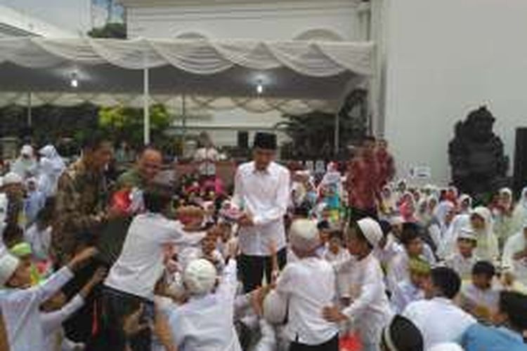 Presiden Joko Widodo membagikan buku tulis saat buka puasa bersama anak yatim dan penyandang disabilitas di Istana Bogor, Selasa (28/6/2016).