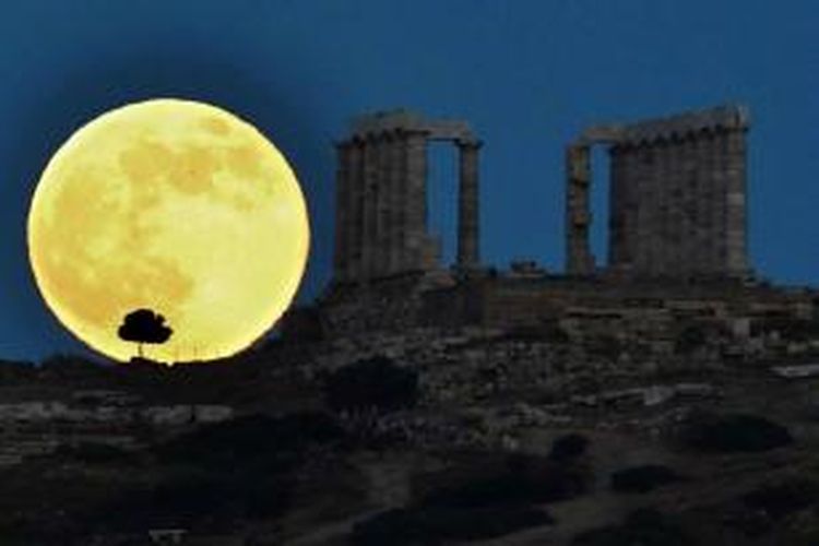 Bulan purnama naik di sebelah kuil Yunani kuno Poseidon di Cape Sounion, sekitar 65 kilometer selatan Athena, 23 Juni 2013. Bulan yang akan mencapai tahap penuh pada Minggu, 14 persen lebih dekat ke bumi dan dikenal sebagai fenomena supermoon.