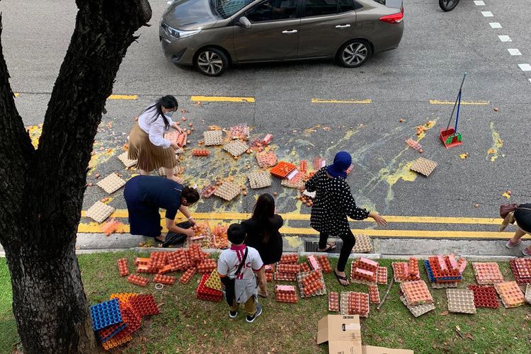 Warga Singapura coba bantu membersihkan telur yang jatuh dari truk di jalanan, Sabtu (11/6/2022).