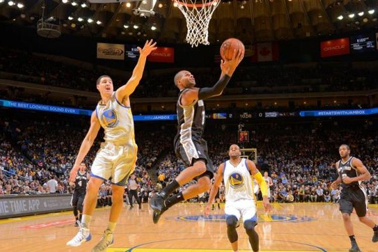 Pemain San Antonio Spurs, Patty Mills (tengah) melakukan lay up di depan pemain Golden State Warriors, Klay Thompson pada laga yang berlangsung di Oracle Arena, Oakland, California, Kamis (19/12/2013).