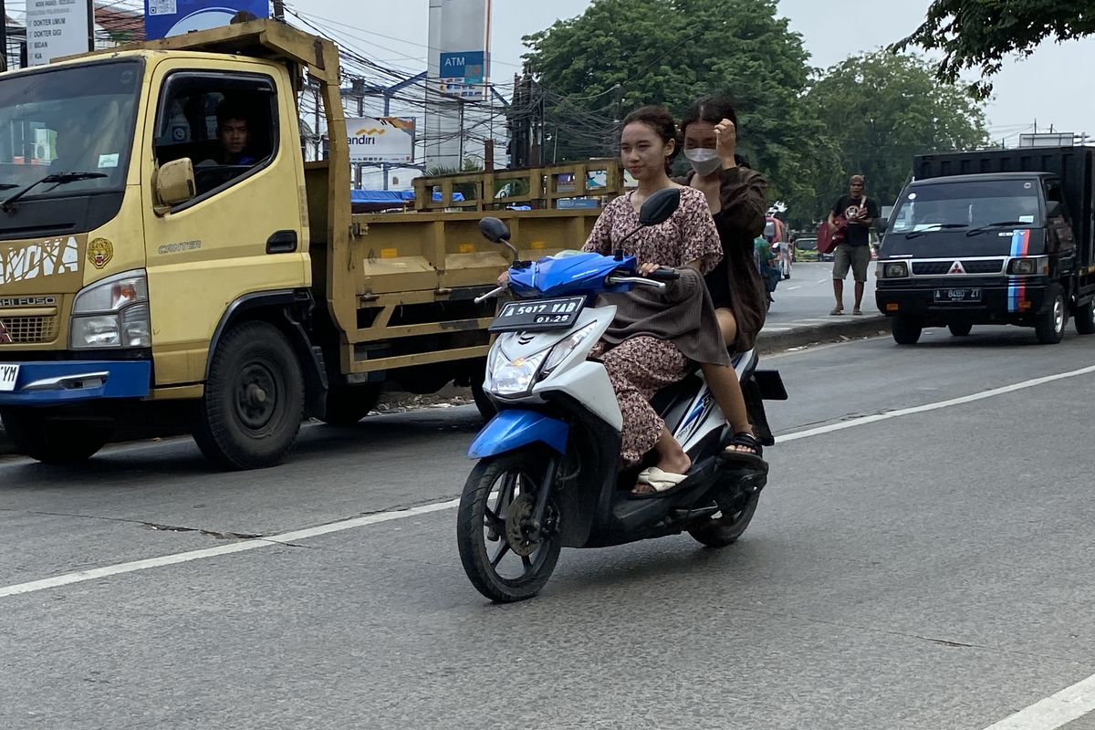 Pengendara motor berboncengan tanpa menggunakan helm di jalan raya
