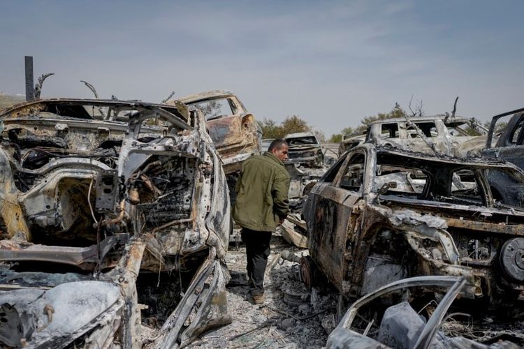 Seorang pria Palestina berjalan di antara mobil-mobil yang hangus di tempat pembuangan sampah, di kota Huwara, dekat kota Nablus, Tepi Barat, Senin, 27 Februari 2023. 