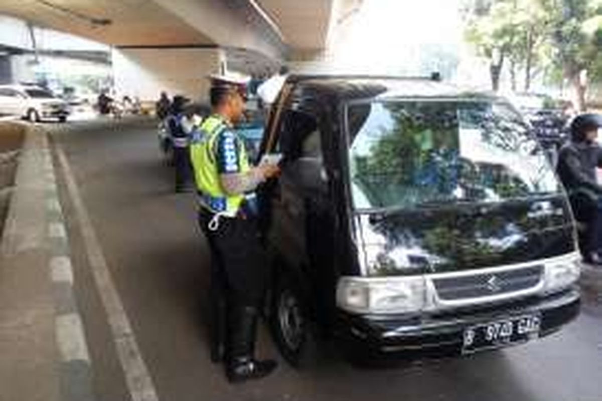 Salah satu kendaraan berpelat genap saat diberhentikan oleh petugas kepolisian karena melanggar aturan ganjil genap di kolong Fly Over Kuningan pada Jumat (5/8/2016).