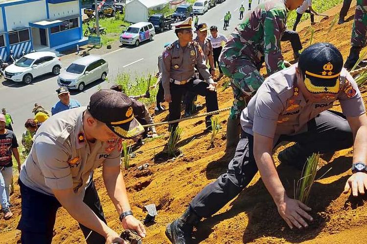 Kepala Polres Tasikmalaya Kota AKBP Anom Karibianto bersama wakilnya Kompol Riki berupaya menanam vetiver dengan menaiki bukit terjal di kawasan tanjakan Gentong, Tasikmalaya, Minggu (8/3/2020).