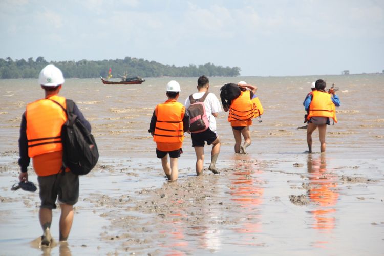 Petugas pembangunan jaringan listrik PLN saat melintasi medan berlumpur di Pulau Nangka.