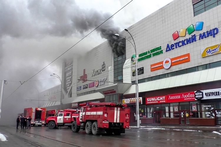 Kendaraan pemadam kebakaran berada di luar pusat perbelanjaan yang terbakar di Kemerovo, Rusia, Minggu (25/3/2018). (AFP)