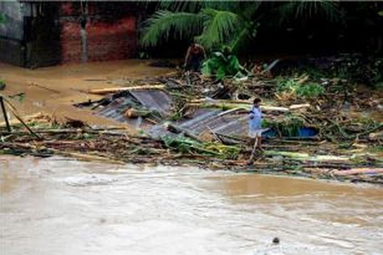 Foto yang diambil tanggal 15 Januari 2014 memperlihatakan seorang warga berdiri di atas atap rumah yang terendam banjir di Manado, Sulawesi Utara.