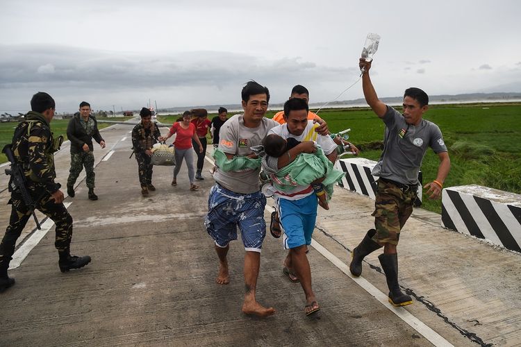 Tentara Filipina membantu sebuah keluarga yang membawa anak mereka yang sedang sakit ke kendaraan pemerintah setelah ambulans tak bisa sampai karena amukan Topan Mangkhut menutupi jalan. Topan tersebut dilaporkan telah menewaskan dua orang.