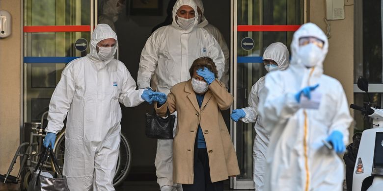 Petugas medis mengenakan pakaian pelindung mengawal perempuan yang diduga terinfeksi virus corona di Istanbul, Turki, pada 12 April 2020.