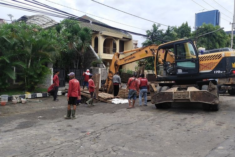 Alat berat dan petugas saat menangani amblesnya tanah depan rumah warga di Surabaya,