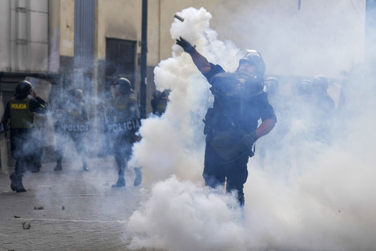Seorang petugas polisi melemparkan tabung gas air mata ke arah pendukung Presiden terguling Pedro Castillo selama protes di Lima, Peru, Senin, 12 Desember 2022. 