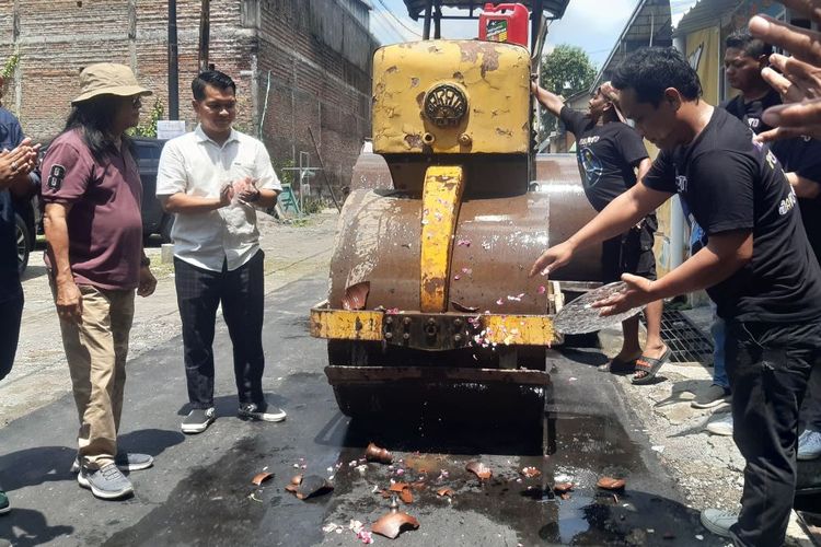 Kakak kandung Ibu Negara Iriana Jokowi, Haryanto atau akarab disapa Pakde Anto disaksikan relawan Tugu Boto Bersatu dan warga desa setempat melakukan prosesi pecah kendi dalam perbaikan jalan penghubung Desa Klodran, Colomadu, Karanganyar dengan Banyuanyar, Solo, Jawa Tengah, yang rusak, Selasa (5/3/2024).