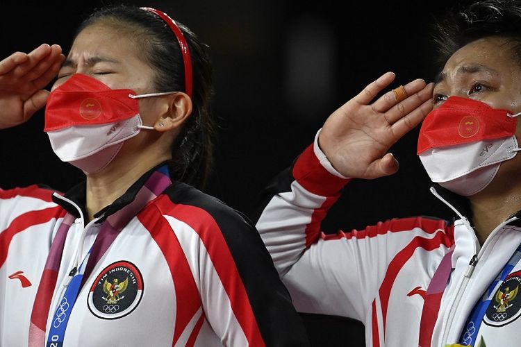 Pasangan ganda putri Indonesia Greysia Polii dan Apriyani Rahayu (kanan) memberi hormat dengan medali emas bulu tangkis ganda putri pada upacara Olimpiade Tokyo 2020 di Musashino Forest Sports Plaza di Tokyo pada 2 Agustus 2021.